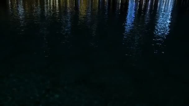 À noite, na superfície da água, os brilhos dos arranha-céus luzes são refletidas — Vídeo de Stock