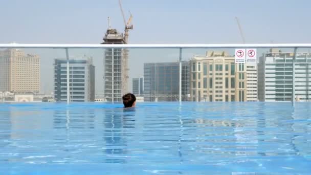 Chica relajante en la piscina en el techo con vista urbana en rascacielos — Vídeos de Stock