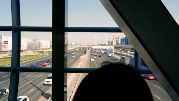 Meisje is permanent in metrostation, passage, kijken naar de bewegingen van het verkeer langs de weg van een drukke stad in middag — Stockvideo