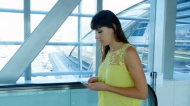 Kız otomatik geçit crossing, akıllı telefon kullanarak, konuşmak metro üzerinde duruyor. --dan pencere eşiği arkasında Trafik yoğun şehir yol boyunca öğleden sonra hamle görebilir miyim