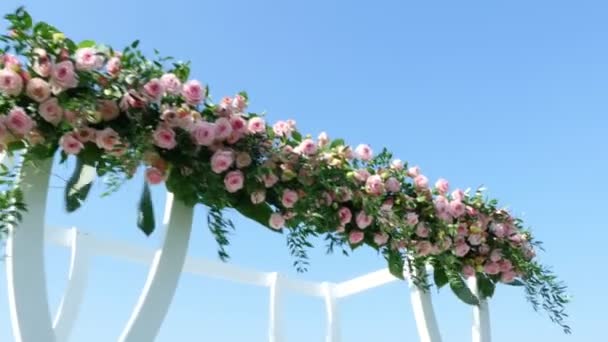 Hochzeitsdekor, weißer Hochzeitsbogen mit Rosen geschmückt, Hochzeitszeremonie am Strand, Vorbereitungen für Hochzeitszeremonie am Strand — Stockvideo