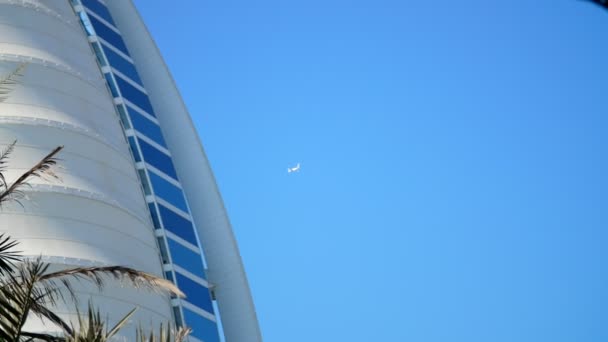 DUBAI, EMIRATOS ÁRABES UNIDOS, Emiratos Árabes Unidos - 20 de noviembre de 2017: Hotel Jumeirah Madinat Burj al Arab. primer plano del hotel, el avión vuela en el cielo sobre el hotel, avión bajo el cielo — Vídeos de Stock