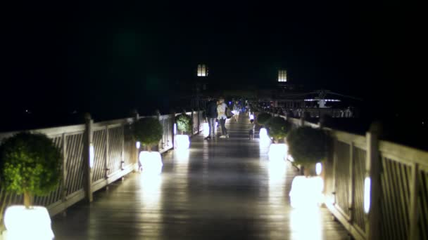 Dubai, Verenigde Arabische Emiraten, Verenigde Arabische Emiraten - 20 November 2017: Hotel Jumeirah Al Qasr Madinat, 's nachts, door licht van lantaarns, mensen wandelen langs de brug naar een restaurant op het water — Stockvideo