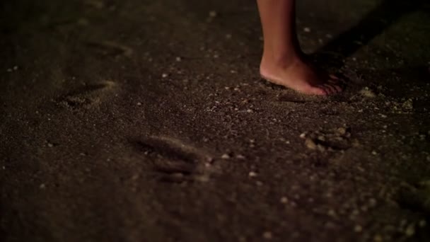 Di malam hari, Pasangan berdiri bertelanjang kaki di pasir, di pantai, dua pasang kaki berdiri di samping, laki-laki dan perempuan. Seorang wanita berdiri di jari-jari kakinya — Stok Video