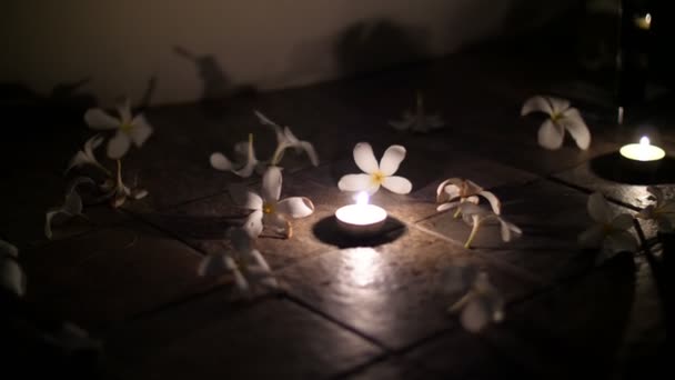 Primer plano, hermosa decoración nocturna en el suelo, velas arregladas y flores dispuestas, magnolias blancas, ambiente romántico, noche, luna de miel — Vídeo de stock