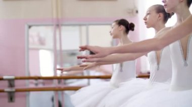 Bale salonunda genç balerinler allonge, eller zarif yukarı ve aşağı, yakın çekim hareket gerçekleştirmek