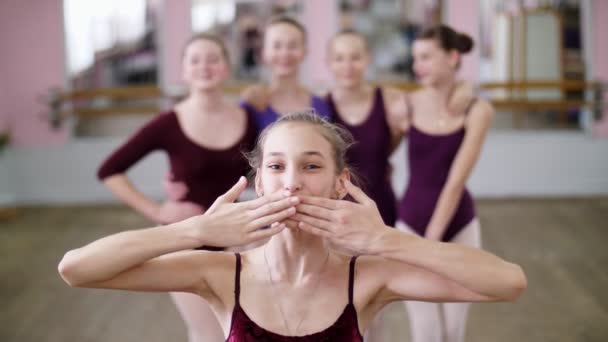 Porträtt av en ung flicka balettdansös i en lila balett trikåer, leende, skicka en air kyss, graciöst utför en balett-figur. — Stockvideo