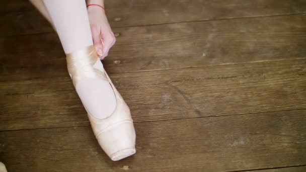 Da vicino, le ballerine si cambiano le scarpe in scarpe da ballo speciali, scarpe da punta, pizzo con nastri da ballo, su un vecchio pavimento di legno, in classe di danza classica . — Video Stock