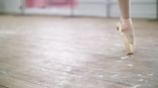 Gros plan, en cours de ballet, sur un vieux plancher de bois, ballerine interprète glissade en tournant, Elle se déplace à travers la classe de ballet élégamment , — Video