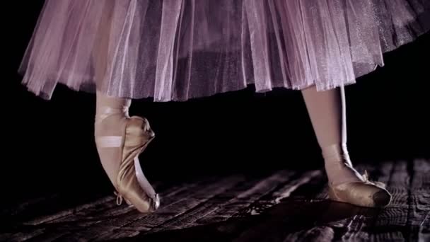 De cerca, en rayos de luz, en el escenario de la antigua sala de teatro. bailarina en falda de ballet blanco, plantea en los dedos de los pies en zapatos puntiagudos, realiza elegantemente un cierto ejercicio de ballet, puntita, tendú — Vídeos de Stock