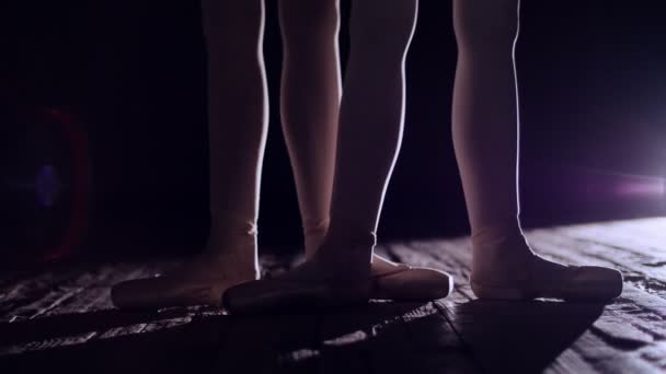 De perto, em raios de holofotes, no palco do antigo salão de teatro. bailarinas levantar sobre os dedos dos pés em sapatos pointe, executa elegantemente um certo exercício de balé, liberar na segunda posição — Vídeo de Stock