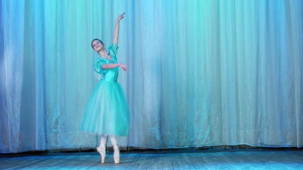 Ballettprobe, auf der Bühne des alten Theatersaals. junge Ballerina in blauem Ballettkleid und Spitzenschuhen, tanzt elegant bestimmte Ballettbewegungen, Arabeske — Stockvideo