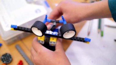 yakın çekim, çocuk eller çok renkli küçük bir robot, makine, bir tasarımcıdan toplandı. çocuklar Robotik, ilgilenirseniz programlama, modelleme,