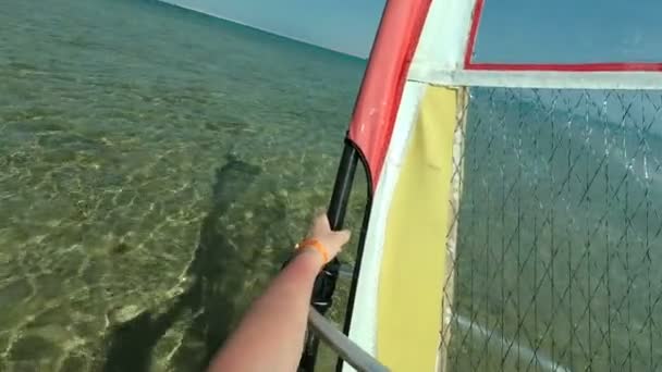 Close-up, a male hand confidently holds a sail against the background of the transparent water of the sea, windsurfing through the eyes of the participant, — Stock Video
