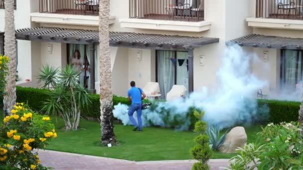 SHARM EL SHEIKH, EGYPTE - 5 AVRIL 2018 : Hotel Jaz Belvedere. L'homme travaille le brouillard pour éliminer les moustiques avec une machine à fumée spéciale. nuages de fumée blanche s'élèvent — Video