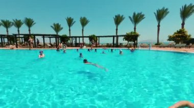 timelaps, dinlenme Havuzu, birçok kişi yıkanmak, yüzme, su aerobiği, fon ve palmiye ağaçlarının karşı meşgul