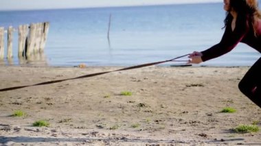 nehir kıyısında plaj. Sunrise, dar elbiseli güzel bir kadın kabuğu doğurmak köpek ile yürüyor, köpek tasması duruyor, bir köpekle oynar, eğlenceli vardır. Yaz