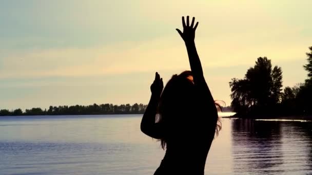 Silhueta da mulher despreocupada dançando na praia durante o belo nascer do sol. vitalidade férias conceito de vida saudável — Vídeo de Stock