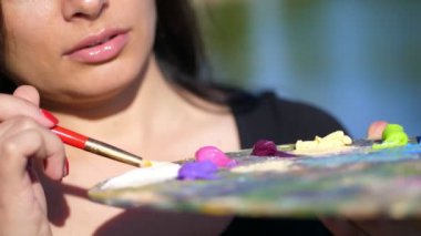 Yaz, açık havada, boyalar, bir paletle close-up kadın sanatçı boyalar Fırça Palet ile karışımları.