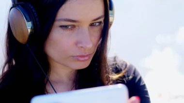 Yaz, açık havada, uzun siyah saçlı güzel bir kadın portresi bir cep telefonundan kulaklıklar müzik dinlemek, aygıt, kendisini telefonla kaldırır, selfi yapar.
