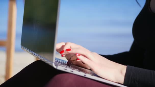 Verano, playa de mar. primer plano de las manos femeninas con manicura de color rojo brillante, tipo en el teclado del ordenador portátil. trabajando en el ordenador portátil , — Vídeo de stock