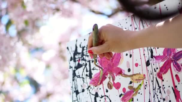 Primer plano, mano femenina, pintor, artista pinta un cuadro de flores en floreciente huerto de manzanas de primavera, aplica pinturas a lienzo con espátula pequeña especial, sostiene la paleta con pinturas — Vídeos de Stock