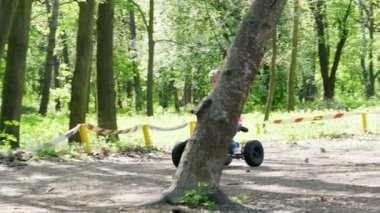 Yaz günü genel pine city Park, parlak pembe tişört ile küçük kız sürme, bir childs sürüş dört tekerlekli motosiklet, mini moto dört, quadricycle pigtails renkli. Çocuklar yaz tatili