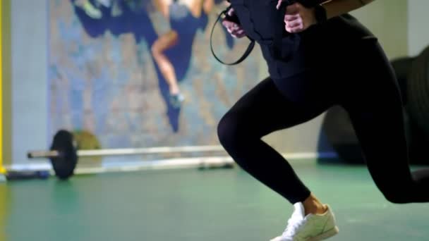 Тренировка с трх фитнес-ремнями в тренажерном зале. крупный план, беременная молодая женщина, с большим животом, в черном обтягивающем спортивном костюме делает упражнения мышцы ног — стоковое видео
