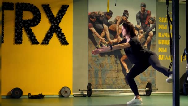 Cherkasy, Ukraina, 20 november 2019: Trx träning. ung gravid atletisk kvinna, med en stor mage, i svart åtsittande träningsoverall, gör övningar med trx fitness remmar i gymmet — Stockvideo