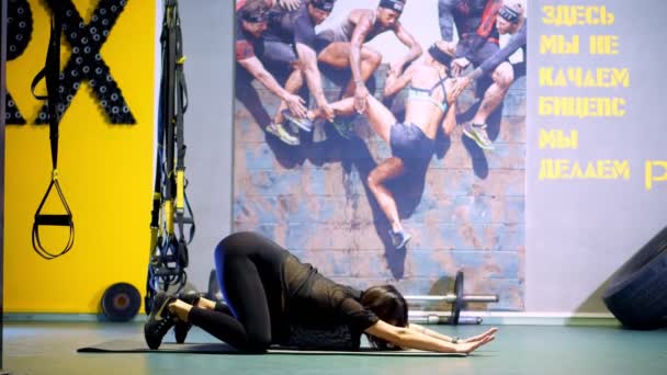 Cherkasy, Ukrayna, 20 Kasım 2019: Geniş göbekli, siyah dar eşofmanlı hamile bir kadın spor salonundaki paspasın üzerinde esneme egzersizleri yapıyor. — Stok video