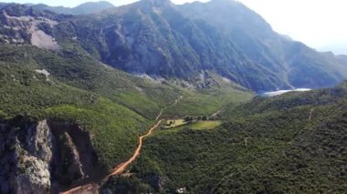 Aero, üst manzara. Yunanistan, Evia Adası. Güzel dağ manzarası. Uçurumun yamacında turkuazlı, mavi suyu olan bir körfez var. Dönek dağ yolu. Yaz sıcak güneşli gün