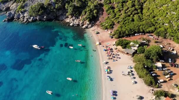 Aero. top view. beautiful summer seascape. wild beach of Evia island, Greece. sea bay with turquoise, blue water at foot of mountains. vacationers sunbathe on beach, many umbrellas, — ストック動画