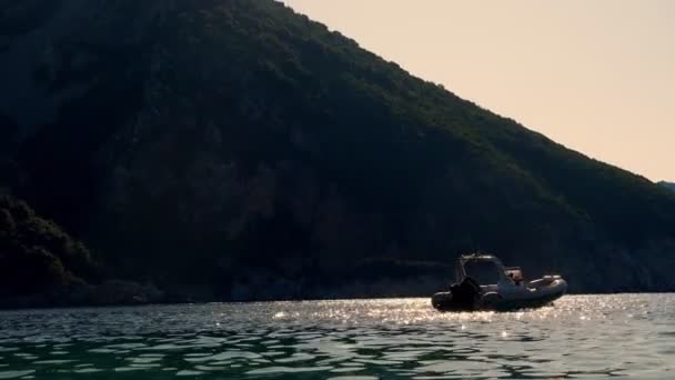 Zatoka u podnóża góry. promienie słoneczne odbijają się w Morzu Egejskim, w miękkich falach, o zachodzie słońca. łódź zacumowana. — Wideo stockowe