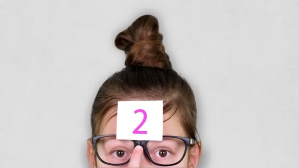Primer plano, una cara de adolescente inteligente, un niño con gafas, con una pegatina en la frente. una animación del proceso de renderización se lleva a cabo en la pegatina . — Vídeos de Stock