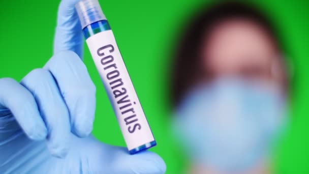 Sobre un fondo verde. primer plano, los médicos entregan el guante médico azul sostiene un tubo de prueba con la inscripción coronavirus. El concepto de medicación para el coronavirus . — Vídeos de Stock