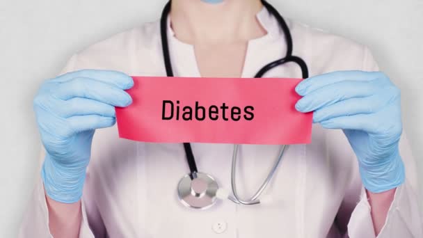 Крупный план, руки в синих медицинских перчатках держат и рвут красную бумажную карточку с надписью "Диабет". врач в белой медицинской форме, имеет стетоскоп . — стоковое видео