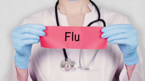 Närbild, händer i blå medicinska handskar hålla och riva rött papper kort med en inskription Influensa. läkare klädd i vit medicinsk uniform, har ett stetoskop. — Stockvideo