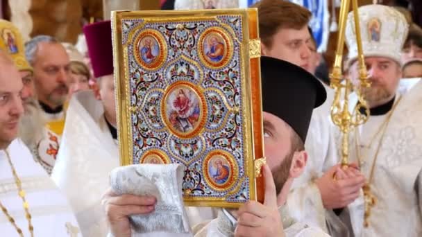 KONKURRENSREGION, UKRAINE, OKTOBER 10, 2019: Närbild håller prästen en stor kyrkbok i en vacker guldbindning. kyrkans invigningsceremoni. — Stockvideo