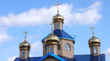 Altın kilise kubbeleri mavi gökyüzü ve beyaz bulutların arka planına karşı. Gökyüzünde bir sürü mavi balon uçuşuyor. Ortodoks Kilisesi.