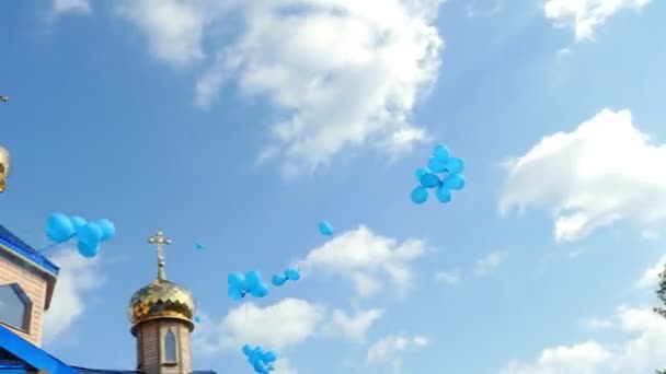 Gyllene kyrka kupoler mot en bakgrund av blå himmel och vita moln. Många blå ballonger flyger i skyn. Ortodoxa kyrkan. — Stockvideo
