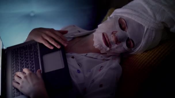 화장품 천으로된 마스크와 머리에 흰 수건을 쓴 여성 사진은 밤에 일하거나 TV 를 보는 동안 노트북 화면 앞에서 잠 이 들었다. 피곤 한 기업인 — 비디오