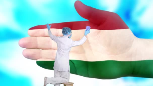 Медсестра в медичній масці і рукавичках миє велику руку, намальовану кольорами прапора Угорщини. Державний догляд за здоров'ям нації. Помий концепцію руки. Захист вірусів. Запобігання хворобам. — стокове відео