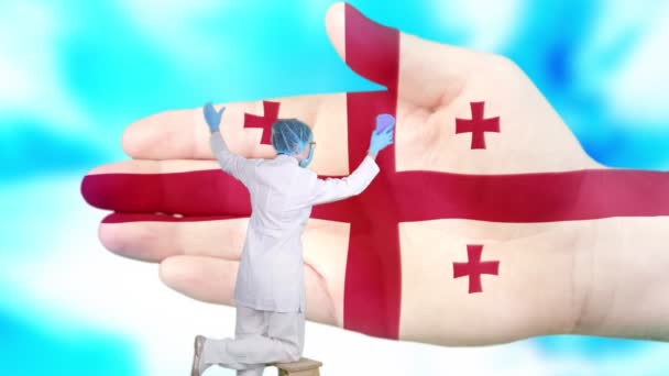 Sestra v lékařské masce a rukavicích myje velkou ruku, malované v barvách gruzínské vlajky. Státní péče o národní zdraví. Umyj si ruce. Ochrana proti virům. Prevence nemocí. — Stock video