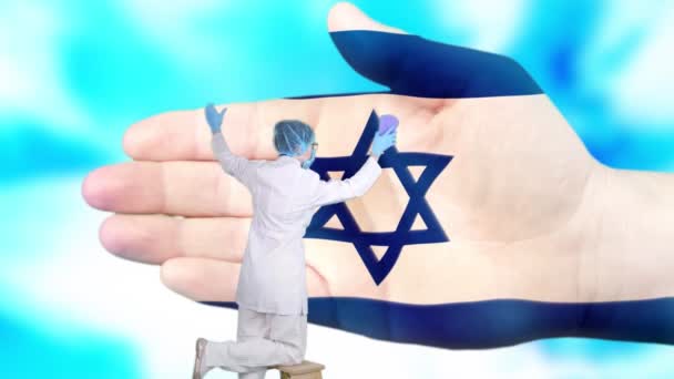 Pielęgniarka w masce medycznej i rękawiczkach myje dużą dłoń, pomalowaną kolorami flagi Izraela. Opieka państwowa nad zdrowiem narodowym. Umyj ręce. Ochrona wirusów. Zapobieganie chorobom. — Wideo stockowe