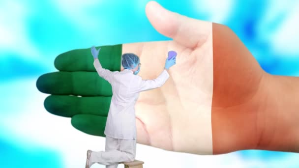 Nurse in medical mask and gloves washes large hand, painted in colors of Ireland flag. State care for nation health. Wash your hands concept. Viruses protection. Diseases prevention. — Stock Video