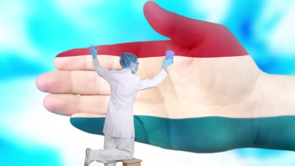 Enfermera en máscara médica y guantes lava la mano grande, pintado en colores de la bandera de Luxemburgo. Asistencia estatal para la salud nacional. Lávese las manos concepto. Protección contra virus. Prevención de enfermedades . — Vídeos de Stock