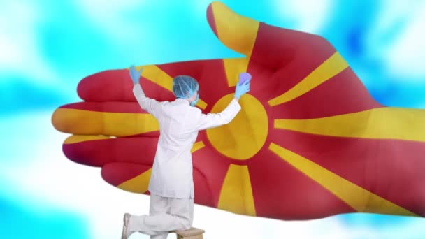 Enfermera en máscara médica y guantes lava la mano grande, pintado en colores de la bandera de Macedonia. Asistencia estatal para la salud nacional. Lávese las manos concepto. Protección contra virus. Prevención de enfermedades . — Vídeos de Stock