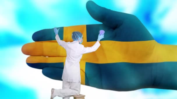 Krankenschwester mit medizinischer Maske und Handschuhen wäscht große Hand, bemalt in den Farben der schwedischen Flagge. Der Staat sorgt für die Gesundheit der Nation. Waschen Sie sich die Hände. Virenschutz. Prävention von Krankheiten. — Stockvideo