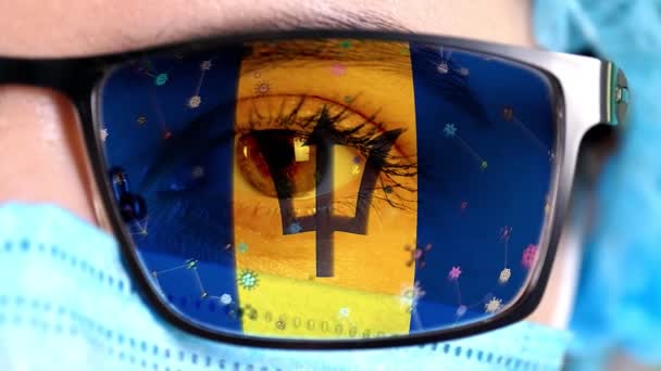 Closeup, eye, part of doctor face in medical mask, glasses, which painted in colors of Barbados flag. Many viruses, germs moving on glass.State interests in vaccines, drugs invention, pathogenic — Stock Video