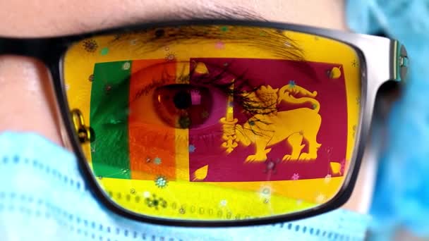 Close-up, oog, deel van de arts gezicht in medisch masker, bril, die geschilderd in de kleuren van Sri Lanka vlag. Veel virussen, ziektekiemen bewegen zich op glas. Staatsbelangen in vaccins, medicijnen uitvinding, pathogene — Stockvideo